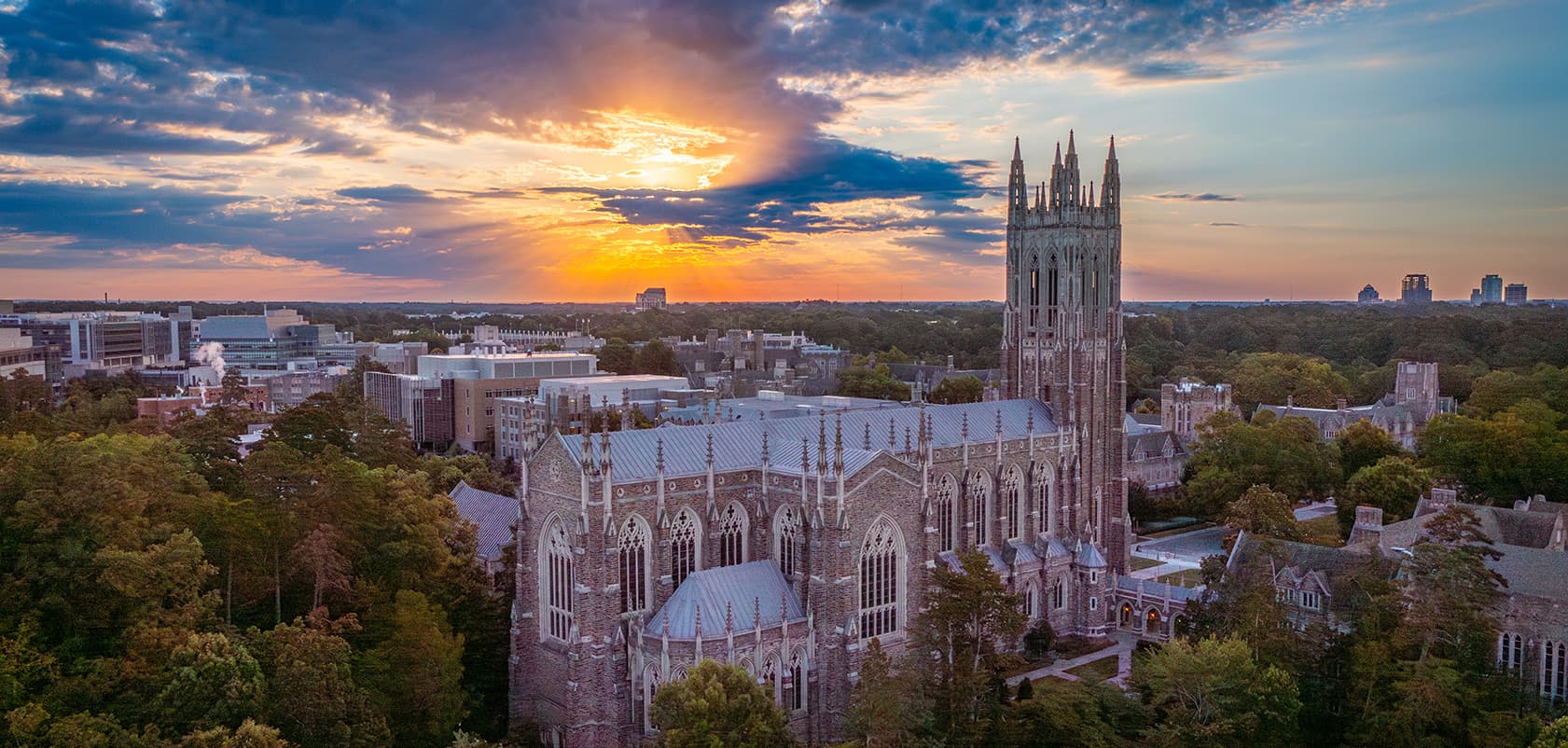 A chapel tower above the trees at sunset